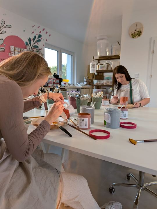 Dwie uczestniczki malujące ceramikę farbami i szkliwami